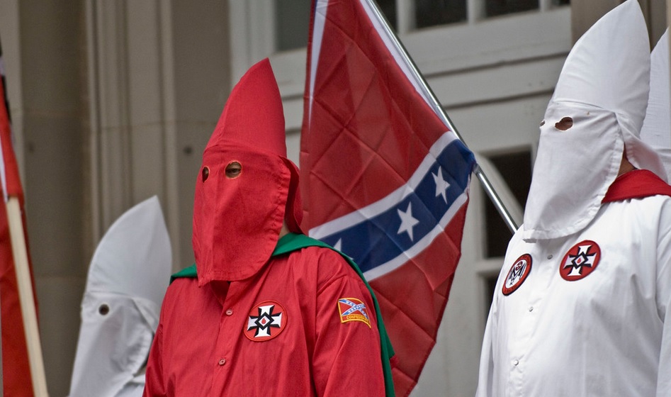 Ku Kux Klan con sus vestimentas típicas delante de una bandera de la Confederación de Estados Unidos. Autor: Martin, 21/11/2009. Fuente: Flickr. (CC BY-ND 2.0.). fascismo