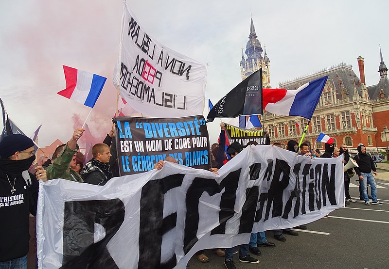 Manifestantes anti-inmigrantes en Calais sostienen una pancarta que dice "La diversidad es una palabra clave para el genocidio de los blancos". Autor: Jérémy-Günther-Heinz Jähnick , 08/11/2015. Fuente: Wikimedia Commons