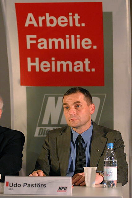 Udo Pastörs, con un eslogan del partido ultraderechista NPD al fondo: "Trabajo, Familia, Patria". Autor: Marek Peters, 26/06/2013. Fuente: Wikimedia Commons
